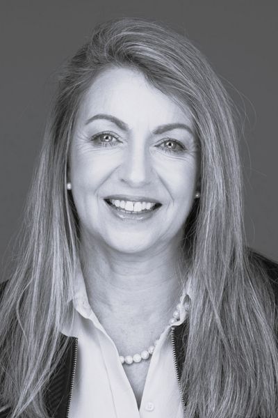 Kerry Sarten, Chair of Ten Days on the Island, smiling warmly, long hair, pearl necklace, looking exactly like someone who chairs a board with both authority and grace.